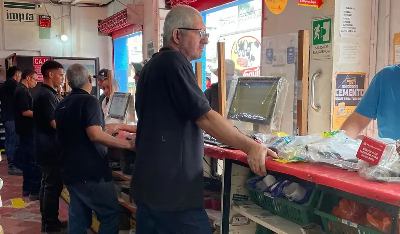 Mostrador de La Bomba con personal atendiendo, clientes y el tablero de turnos