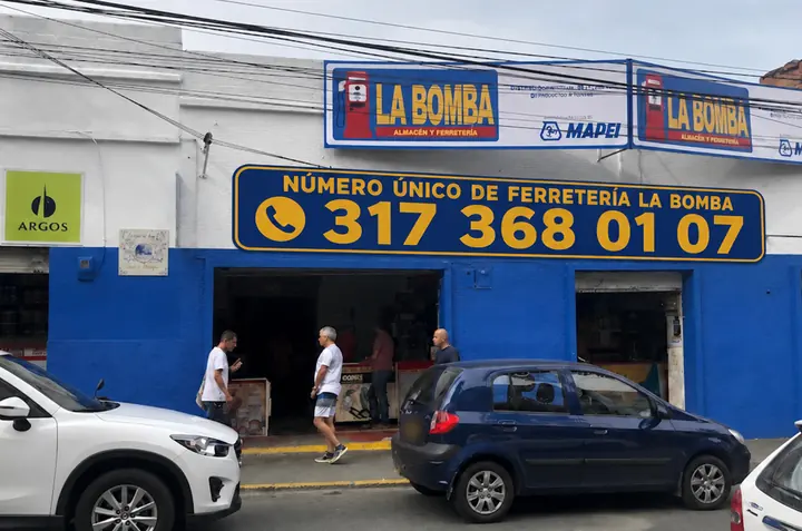 Fachada de La Bomba: muro azul, letreros de La Bomba y el aviso con el número 317 368 01 07